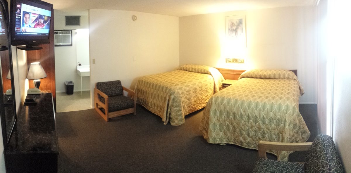 Two-queen guest room with flat-screen TV and seating area